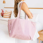 Woman holding a pink/purple linen tote bag in a living room setting