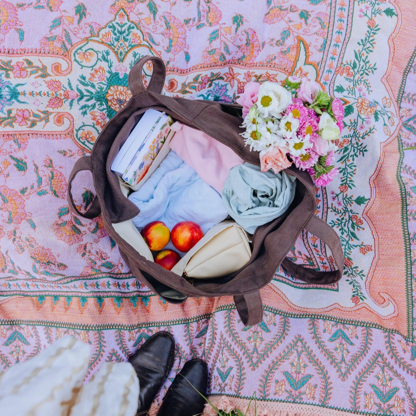 Brown linen tote bag with picnic items on a colorful patterned blanket