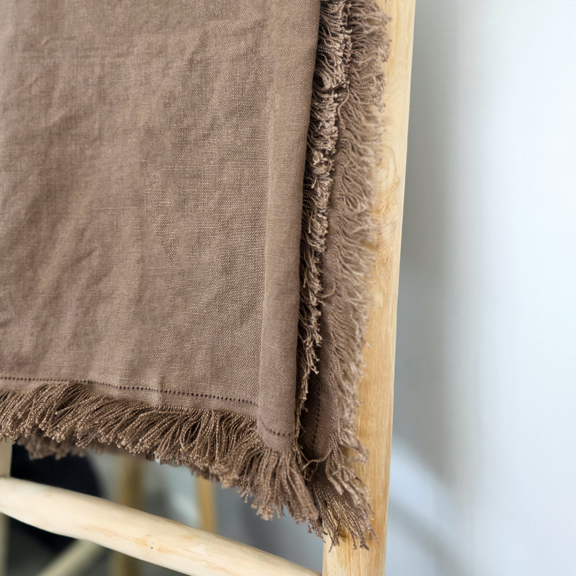Heavyweight 560gsm pure linen throw with fringed edges styled in modern living room