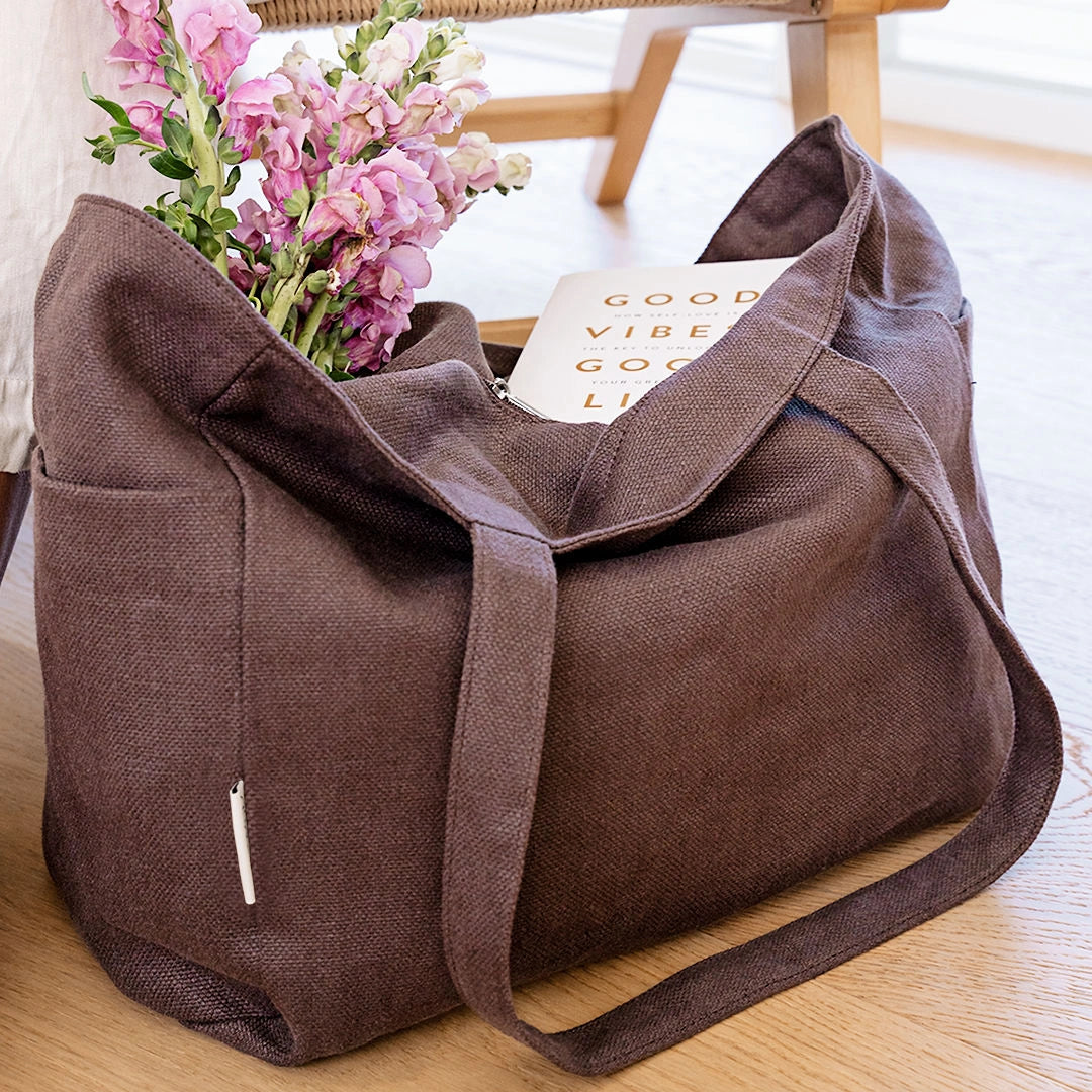 Brown tote bag with flowers and a book on a wooden surface