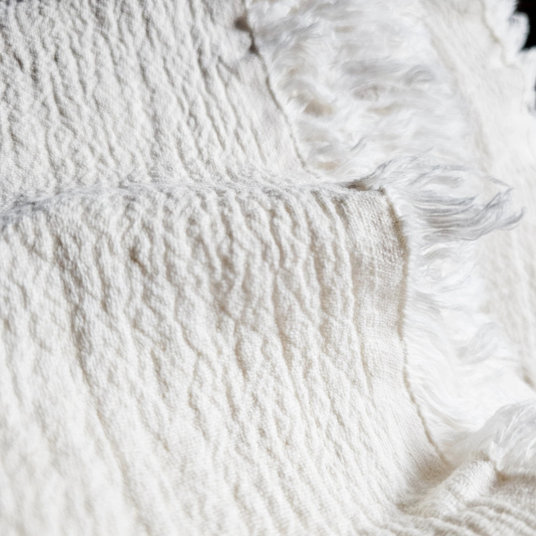 Close-up of textured white linen fabric with fringes