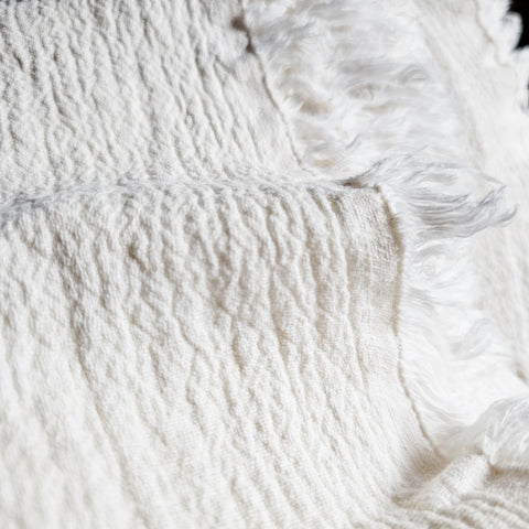 Close-up of textured white linen fabric with fringes