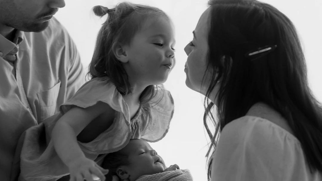 Black and white photo of a family with a young child on a plain background