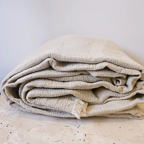 Natural Linen/Cotton throw blanket folded on a marble stone top