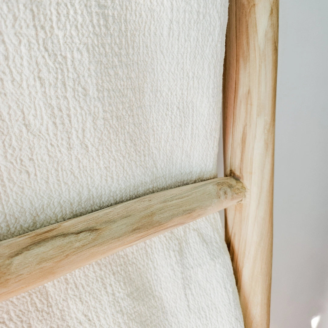 Close-up of a wooden frame with a textured white linen blanket throw background
